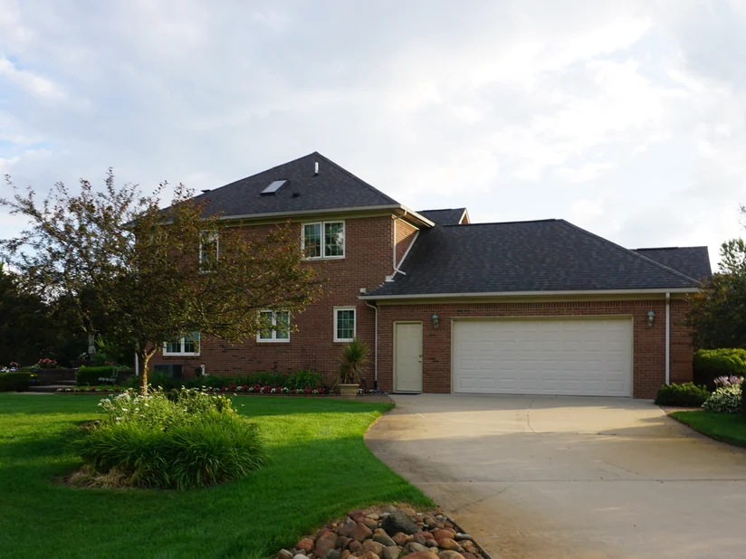 The house from the front lawn in 2019, the brick reading as one even red range across the two-story block and the garage wing.