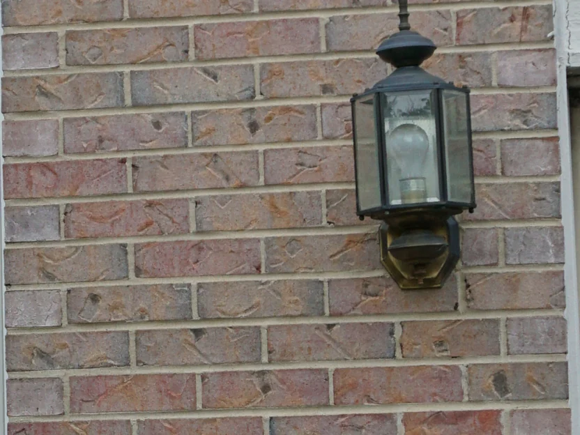 Close view of the brick beside the carriage lantern in 2019, the units running pale pink, buff and grey with cream mortar joints