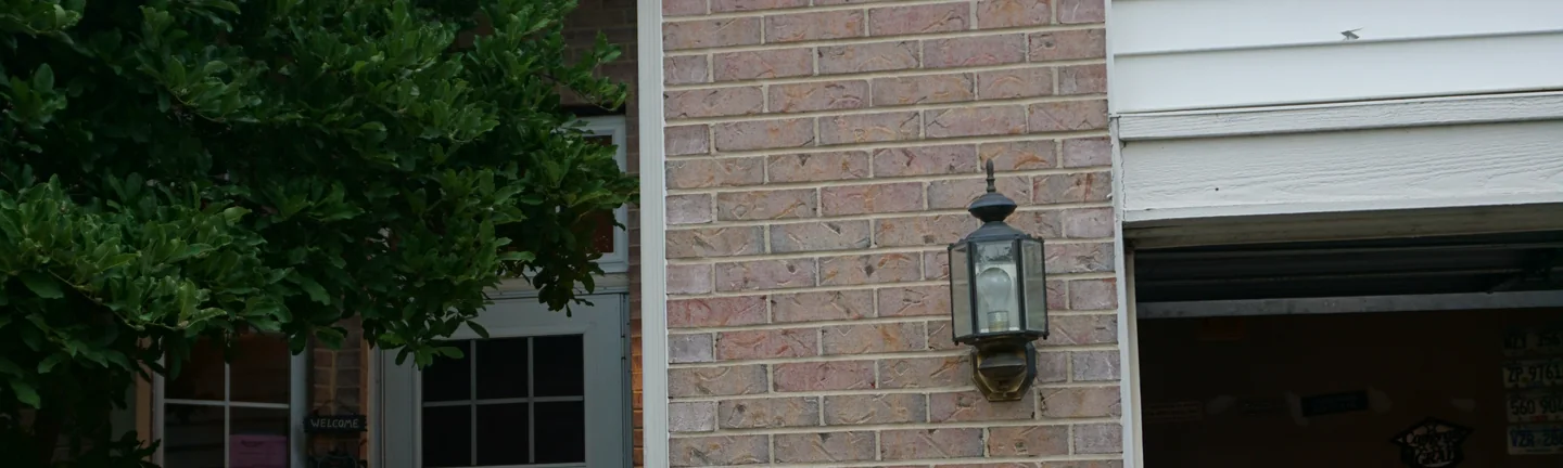 The brick pier between the front door and the garage of the Romeoville home in 2019, a pale pink and buff blend under a carriage lantern