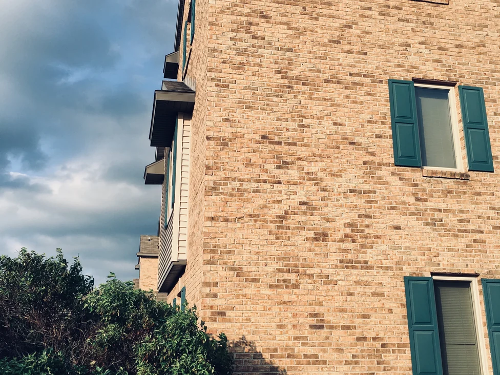 A brick end wall at Royal Vista in 2019 with the balconied wing running back behind it, the brick one buff and tan range across both