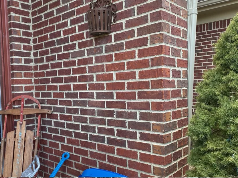 The same outside corner in 2020, the pier and both walls in one range of red brick with even mortar joints, a wooden sled leaning against the wall