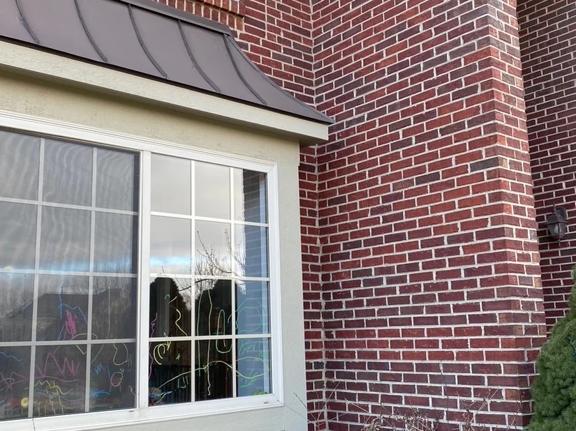 The bay window and the pier beside it in 2020, brick running one range from the window return to the outside corner under a dark metal bay roof