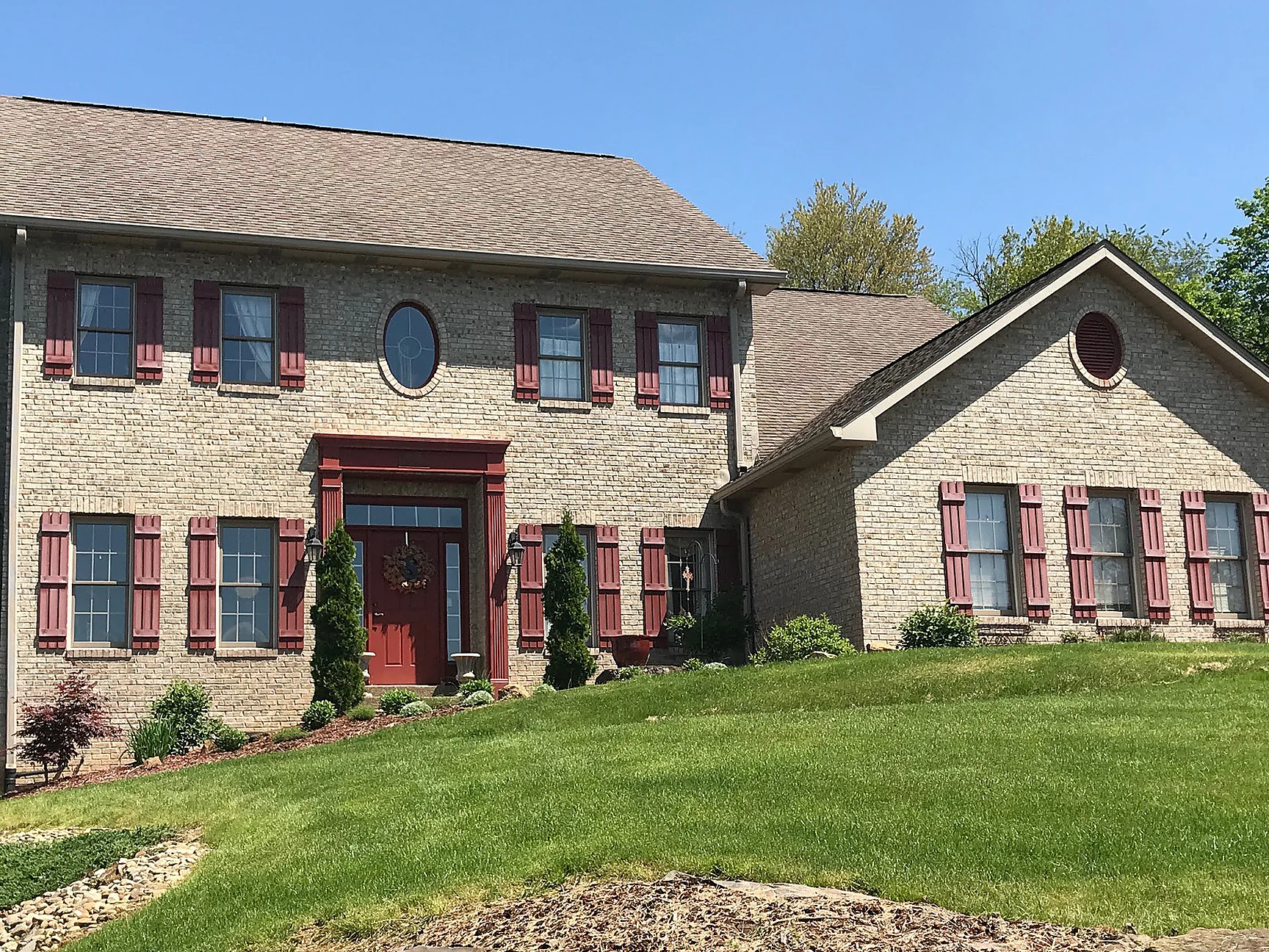 The house from the lawn in 2019, the brick carrying one even color from the entry across to the far wing