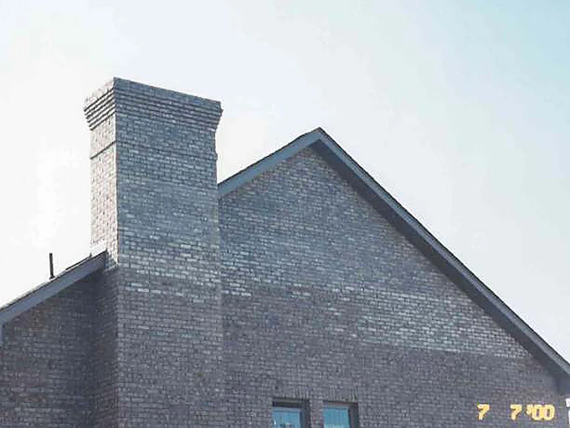 The gable end and chimney of the house in 2000, the brick a cold blotched gray from the eaves down
