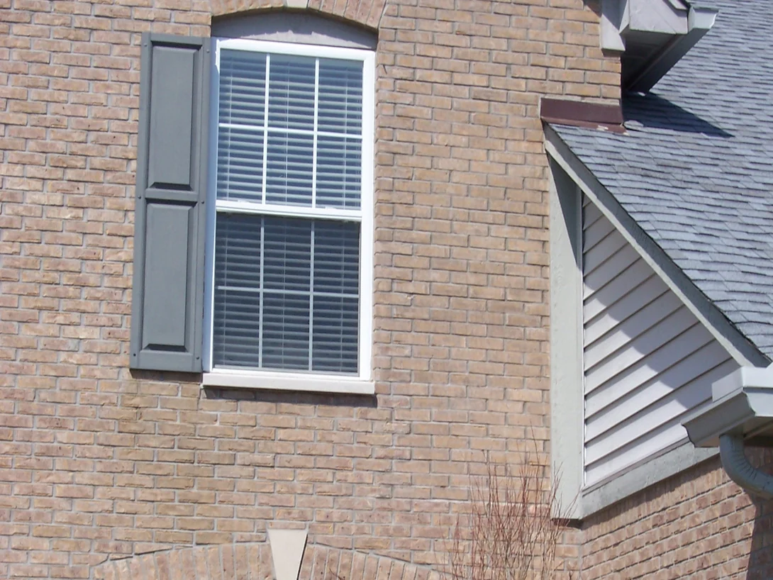 The same window and dormer with the work done, shot in full sun, the brick reading as one tan and brown range