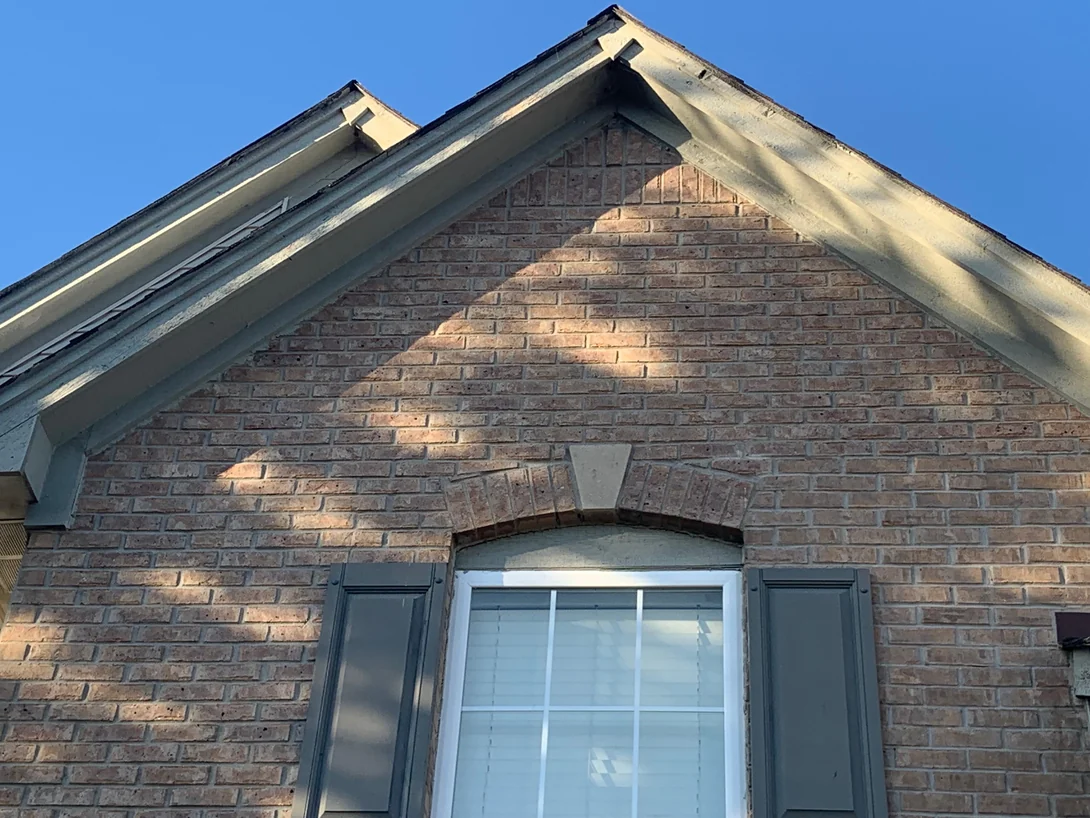 A gable in 2019 centred on its arched window head and cast stone keystone, the brick above and below in the same tan and brown range
