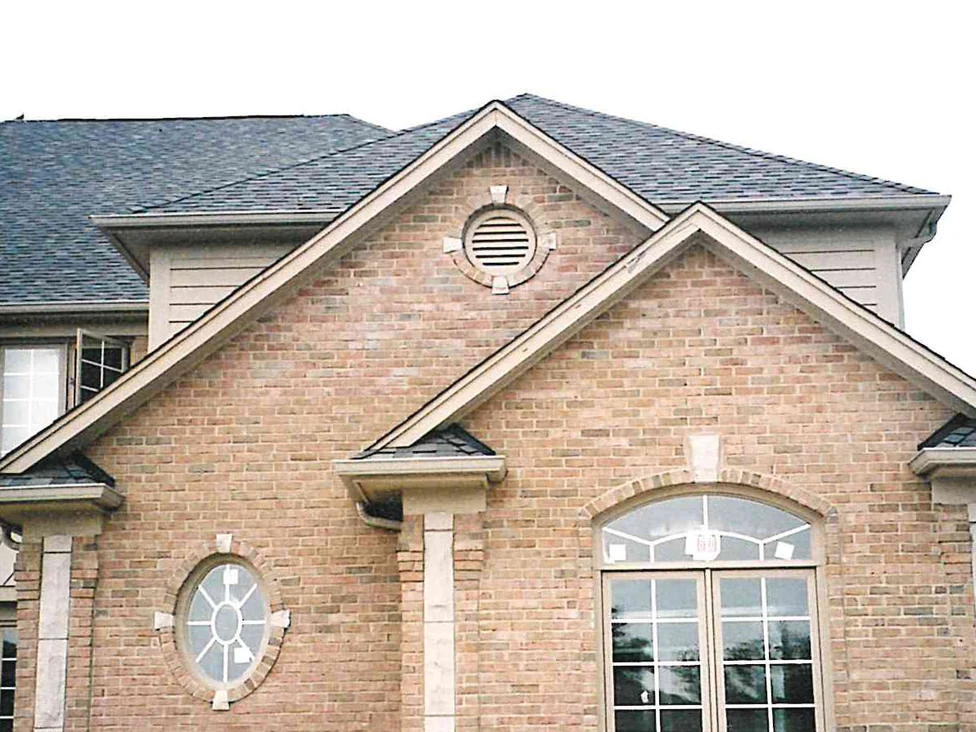 The same gabled wing close up in 2002 while the work was under way, a round louvred vent in the gable above an oval window and an arched double window, the brick a warm tan and pink range