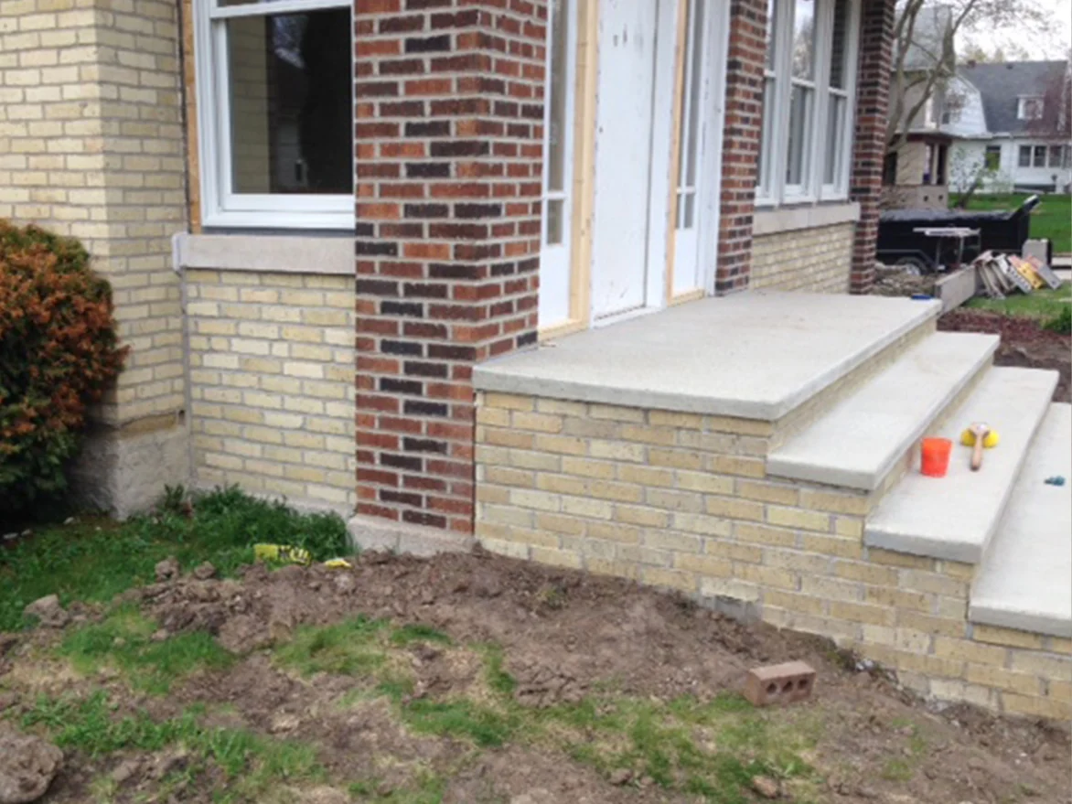 The same entry in 2013 with the porch wall under the steps carried to the cream of the house while the pier beside the door is still red brown, a bucket and brush on the top step