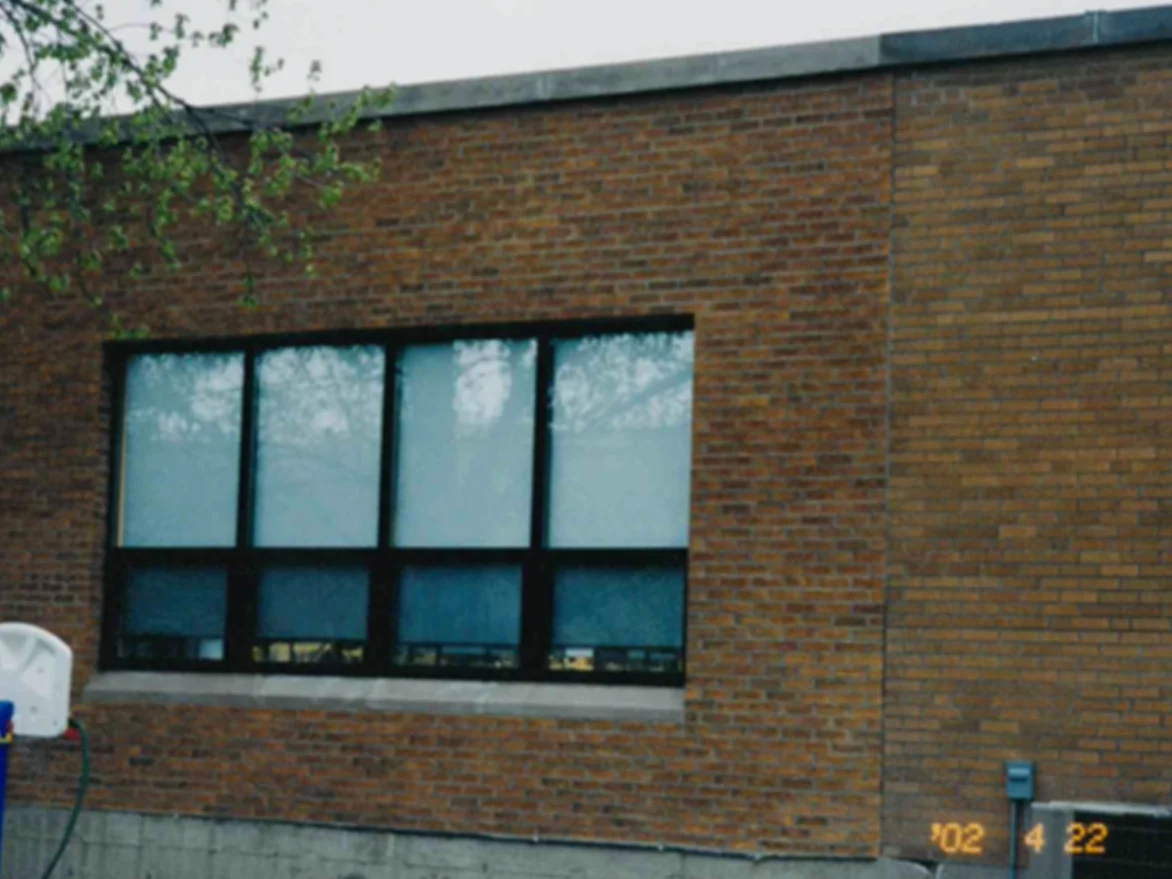 The same window bay in April 2002 after staining, the new section now tan and reading with the existing wall on the right, the camera date stamp in the corner