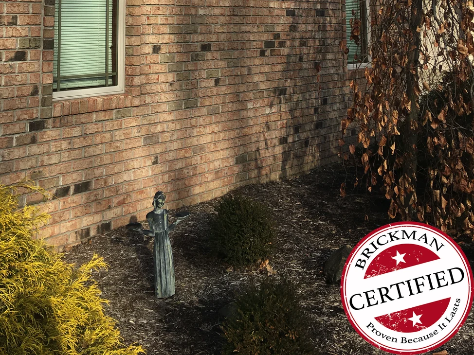 The gable wall of the Slippery Rock house in 2020, the brick one blend from the tall window down to the planting bed, with the certification stamp in the corner