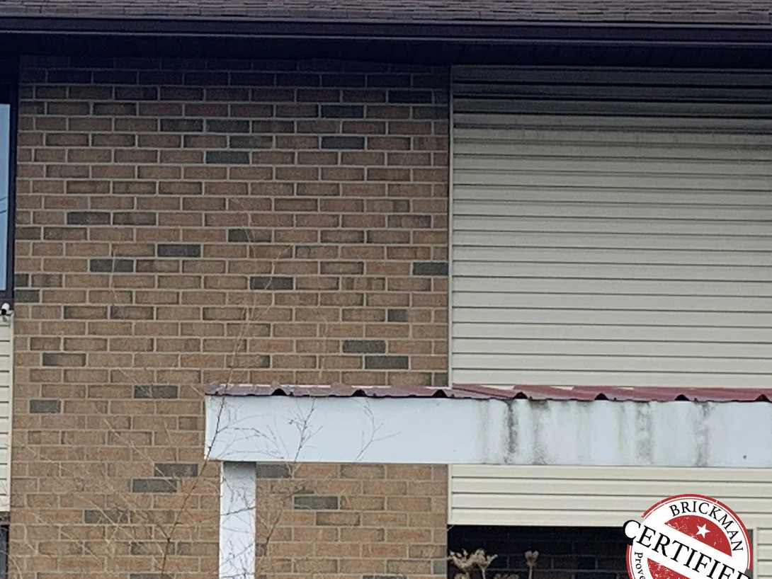 Close view of the stained brick in 2019, darker units distributed through a buff and tan field, with the certification stamp at the lower right
