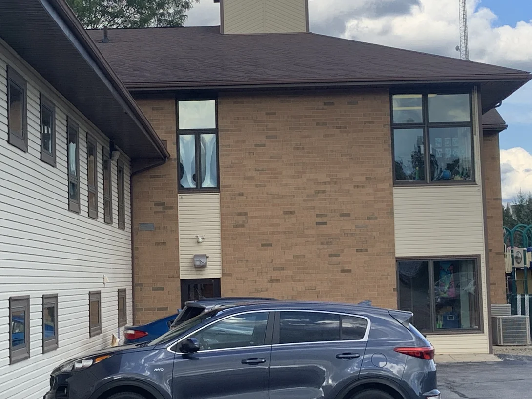 A two-storey brick pier and its windows in 2019, the stain reading as one even range from the ground to the eaves