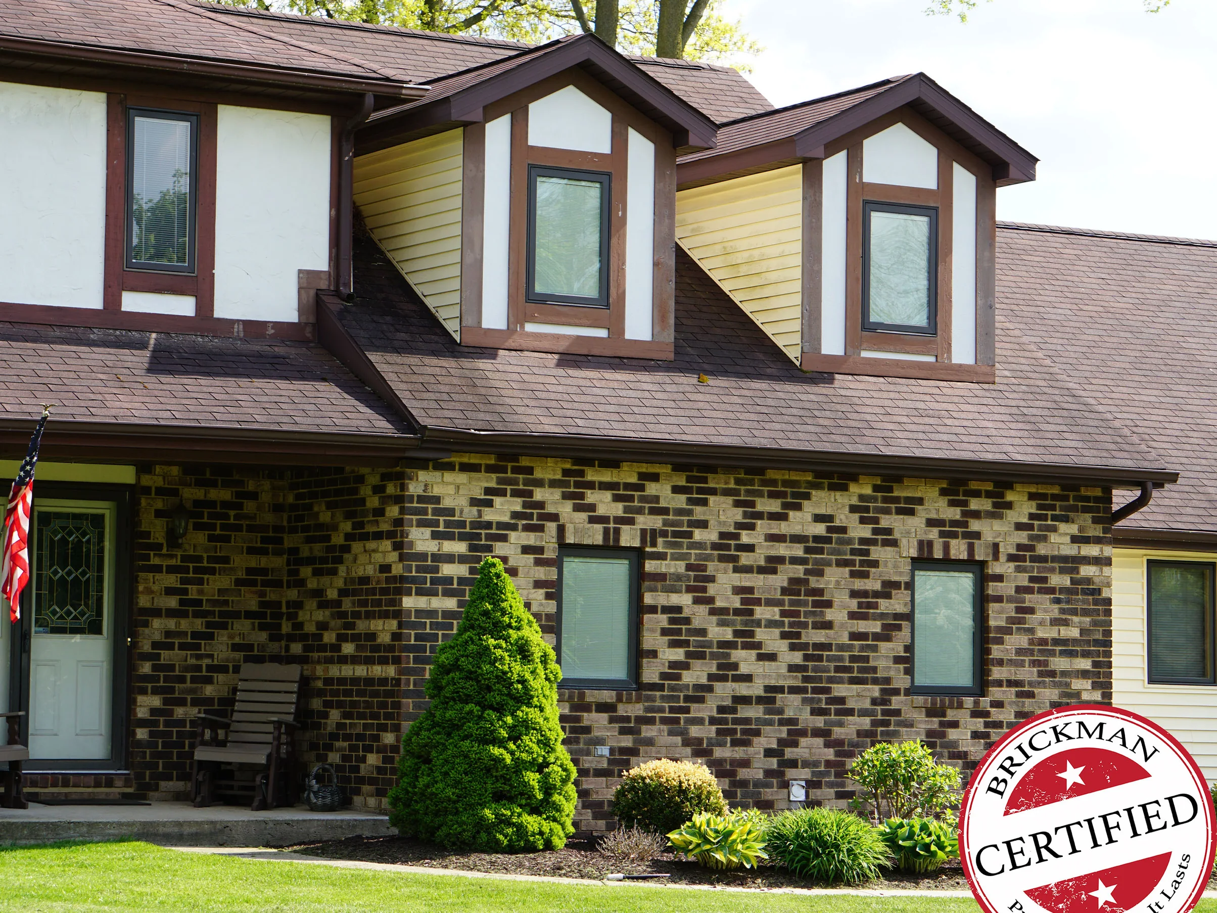 The front of the home in 2019, the entry, the dormered bay and the wall beyond it all carrying the same blend of tan, cream and dark brown brick