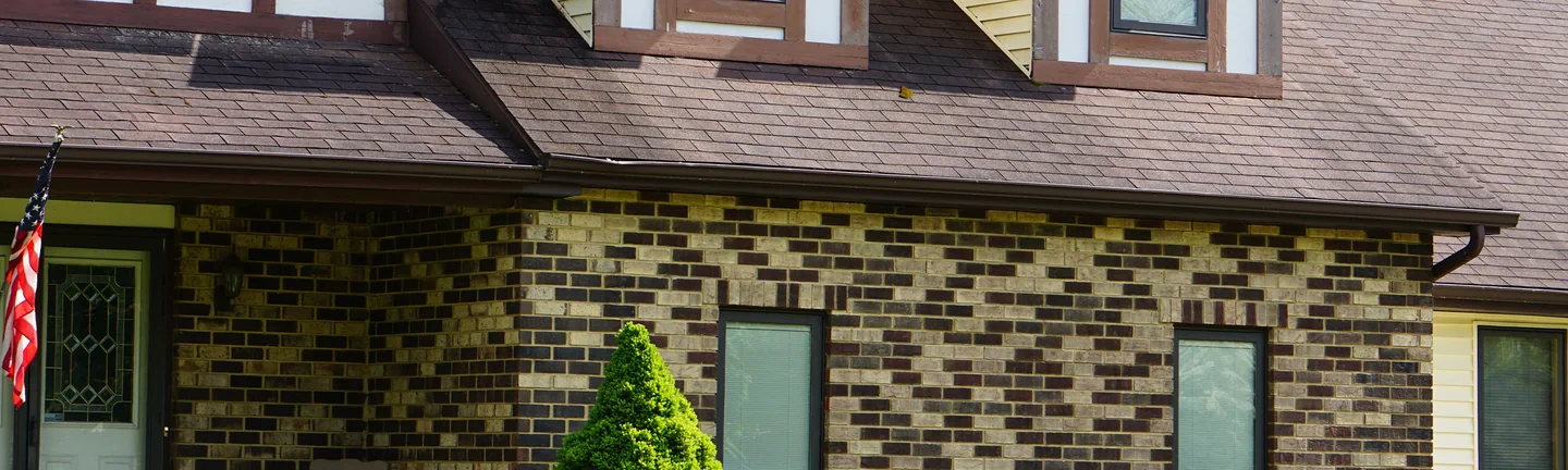 The front of a two-story home in 2019, its brick reading as one blend of tan, cream and dark brown across the wall