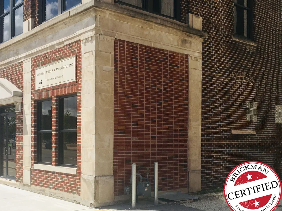 The corner of a downtown architect's office in 2019, its stained alley wall an even red and brown blend
