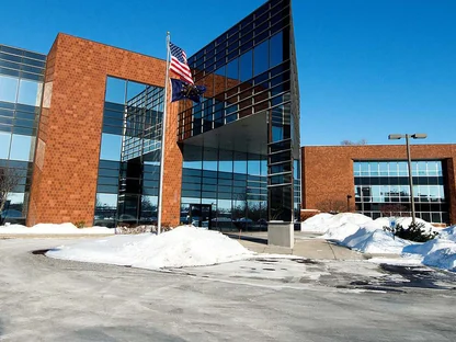 A brick and glass office building under a clear sky, the 2002 addition and the 1950 block reading as one wall