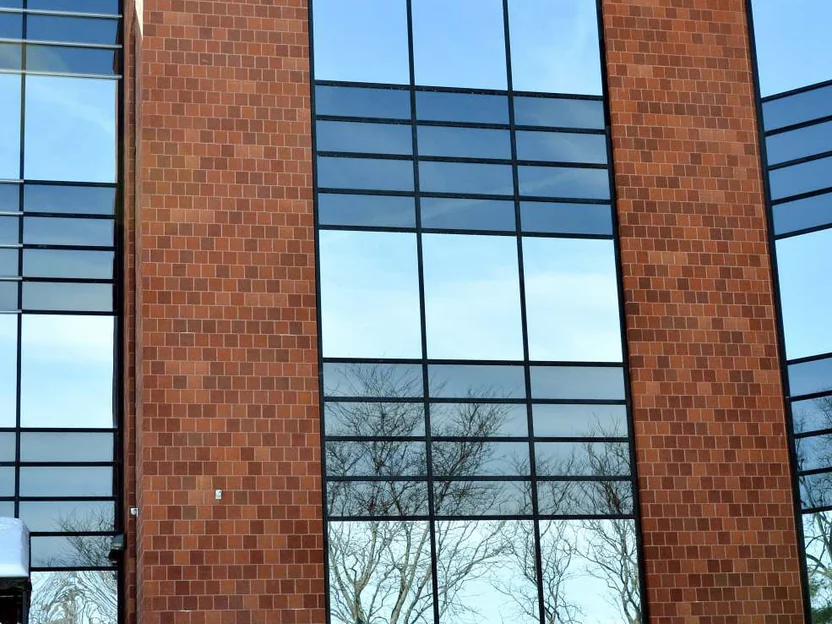 The same stair tower and tall window in 2014, its brick now a mix of reds, browns and darker units across every course, with bare trees mirrored in the glass