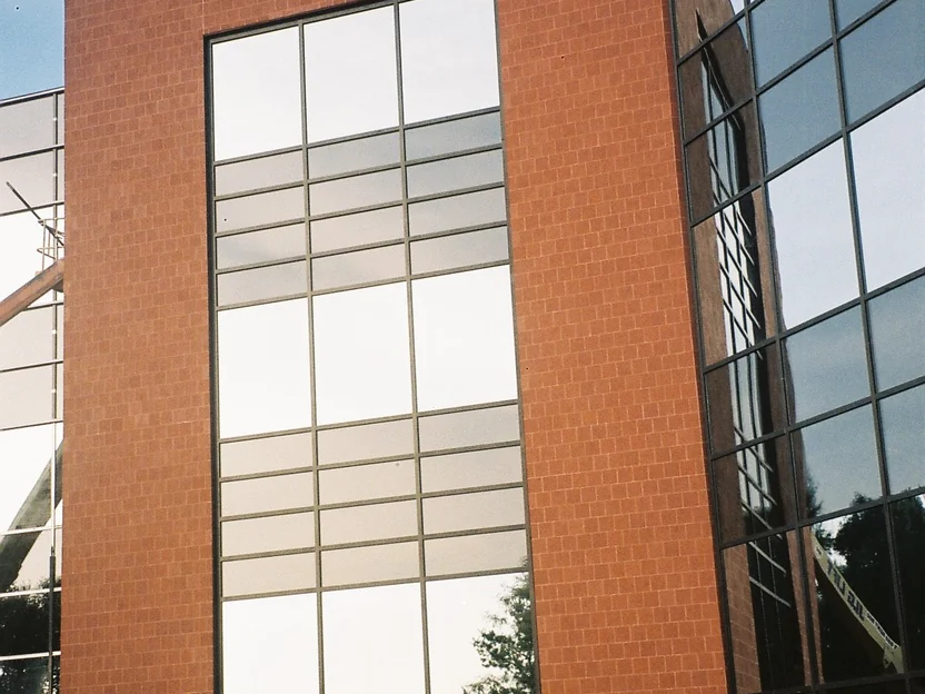 The stair tower of the new wing in 2002, its brick one flat orange red across every course, beside a tall window and the mirrored curtain wall of the older block