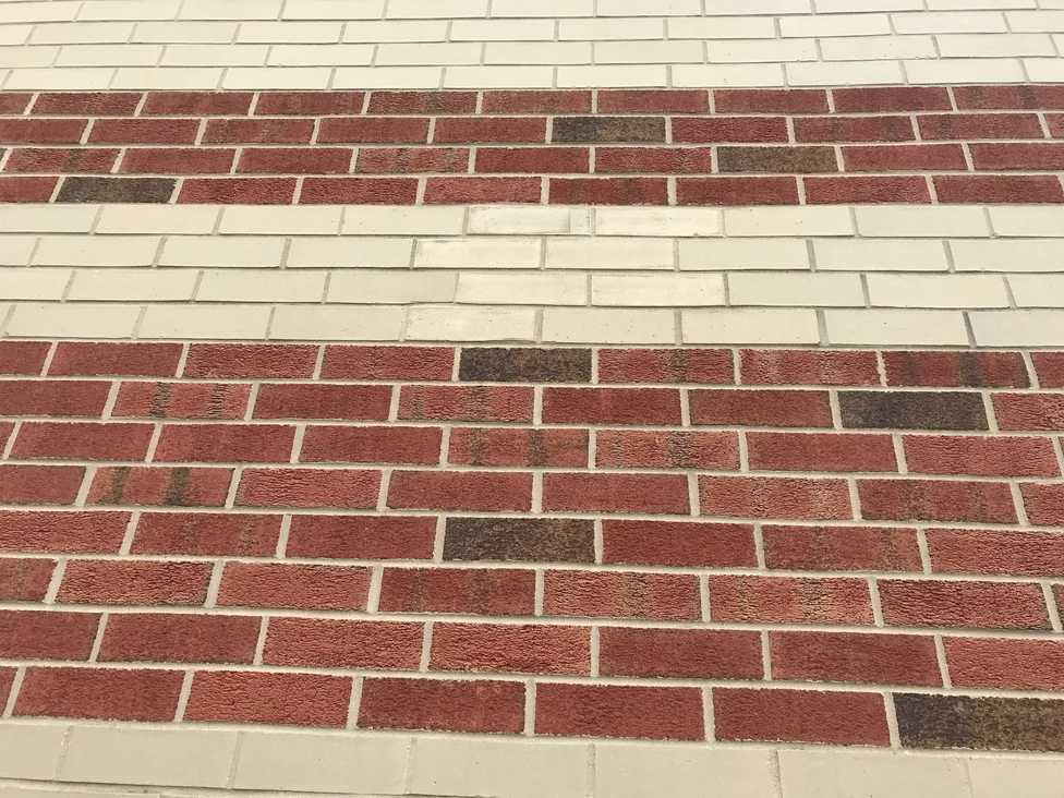 Close view of the banded brickwork in 2019, red units with a few darker ones scattered through the courses above and below a cream band