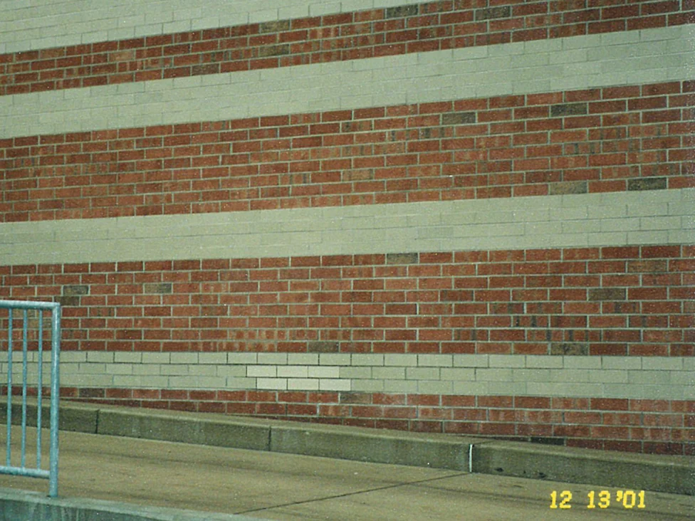 A banded wall in 2001, red courses between pale bands, with a block of replacement brick sitting lighter than the course it was set into