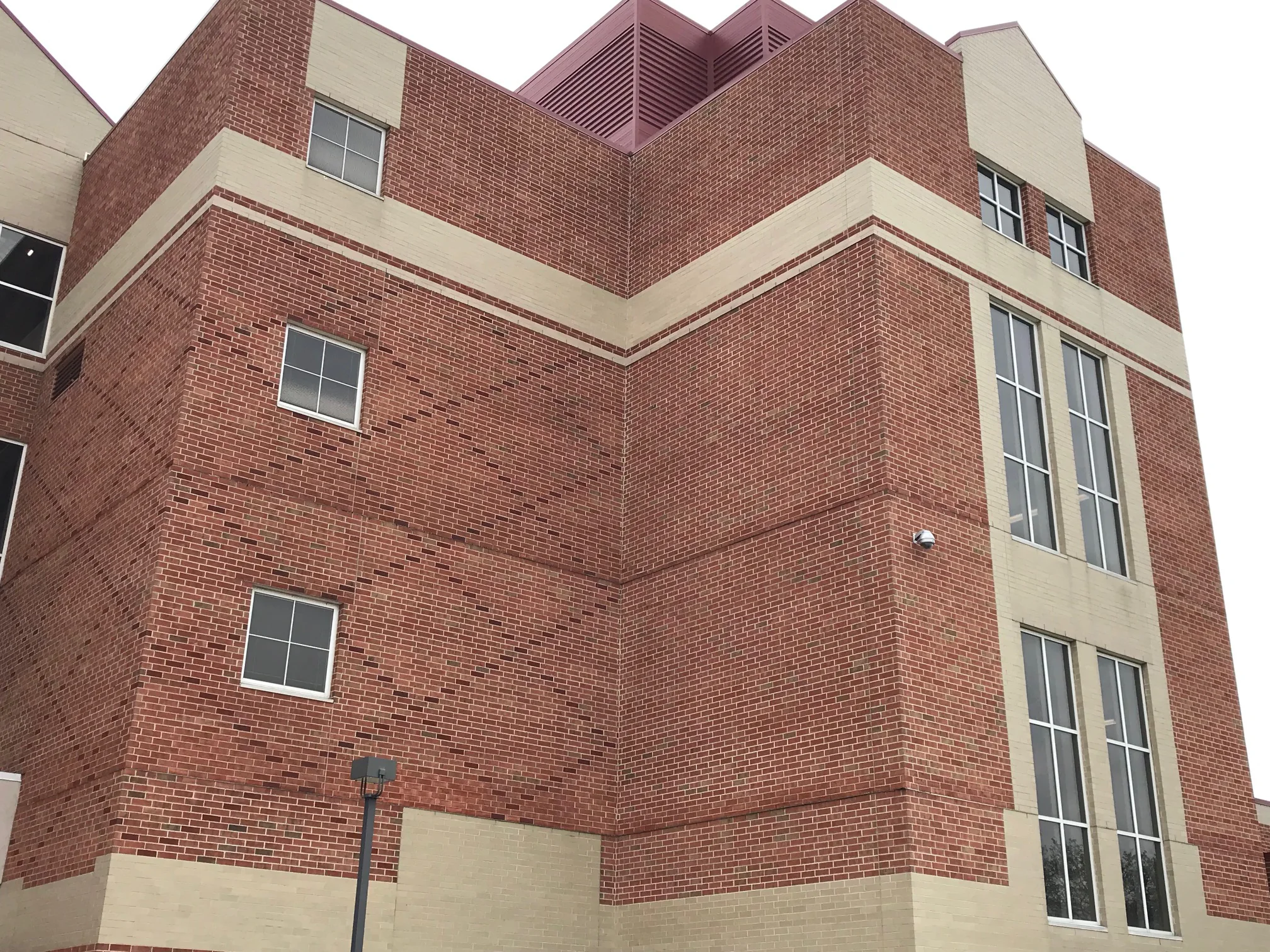 The corner of the school from ground level in 2019, three storeys of red brick banded with buff, windows on both elevations meeting at the corner