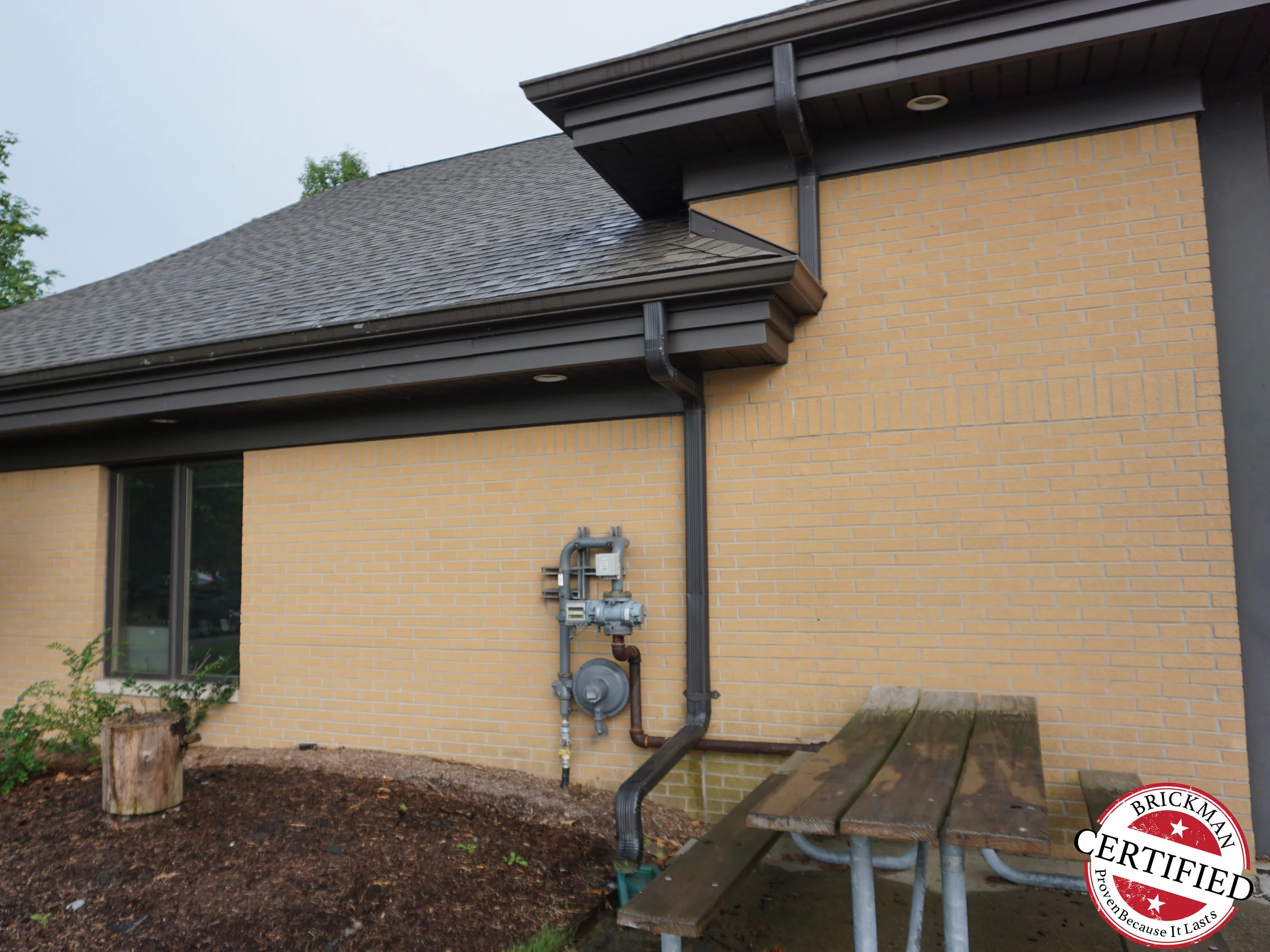 The corner of the fire station in 2019, the brick running one even buff color from the ground to the eaves on both faces