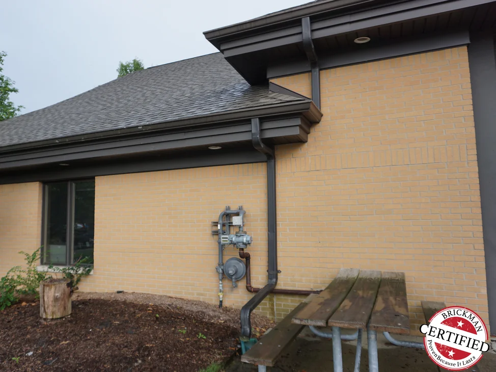 The corner of the fire station in 2019, the brick running one even buff color from the ground to the eaves on both faces.