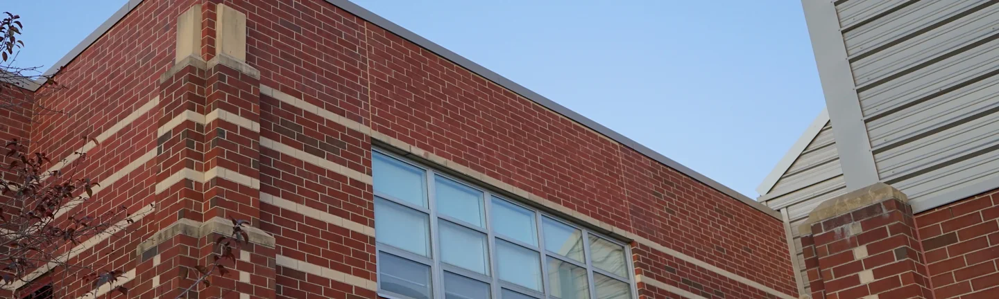The St Clair middle school wall in 2019, red brick running one range with darker units through it and a cream limestone band across the elevation