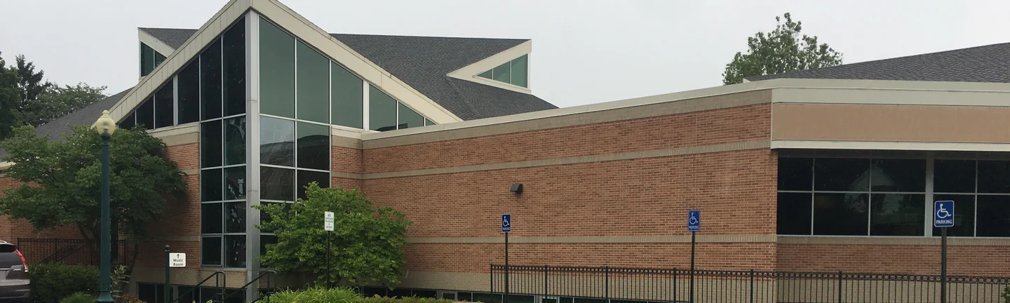The church in 2019, its gabled glazed nave standing beside a long brick wing banded in cream brick