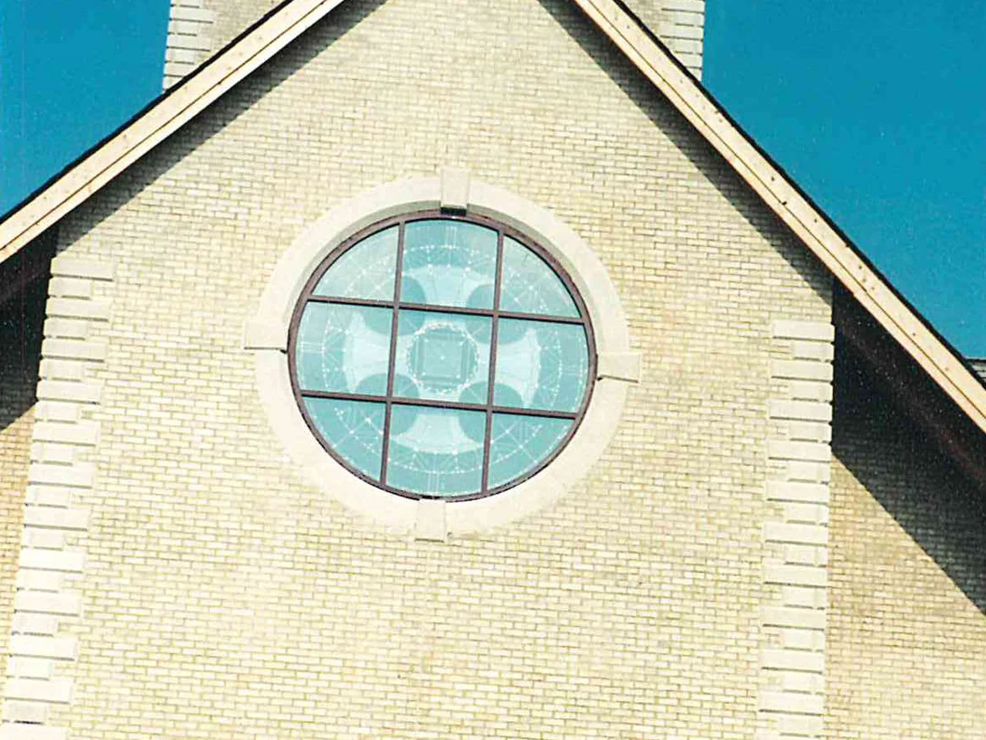 The gable end after the work, the brick reading as one cream and buff range up to the round window