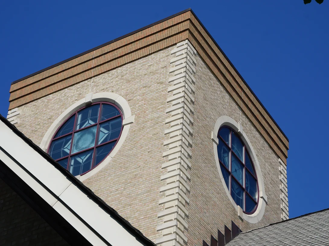 The brick lantern above the roof in 2019, two oval leaded windows in cream brick under banded brown courses