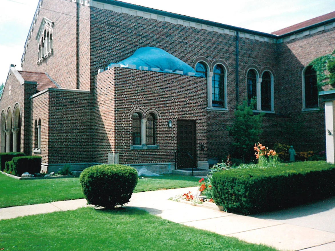 The same wing after staining, its brick carrying the reds and browns of the church walls on either side of it