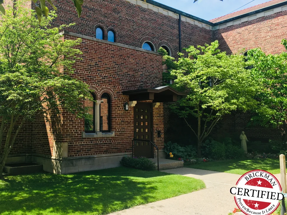 The church wing and its entrance seen across the lawn in 2019, the wing and the older walls behind it reading as one brick