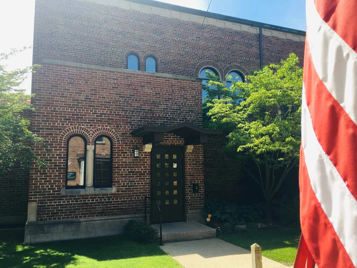 The front of the wing in 2019 with an American flag at the kerb, its arched windows set in even red and brown brick