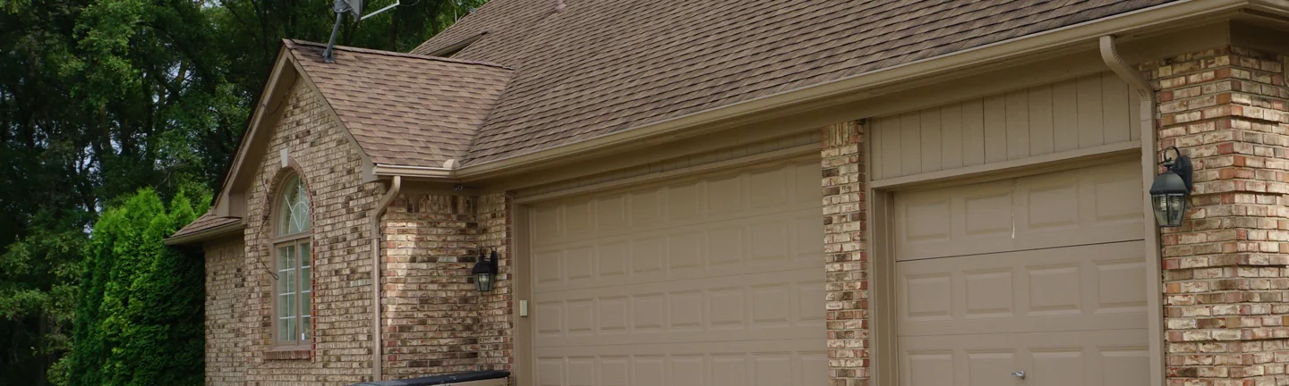 The Sterling Heights house from the driveway in 2019, its brick one even tan and brown range across the gable end and the garage bays