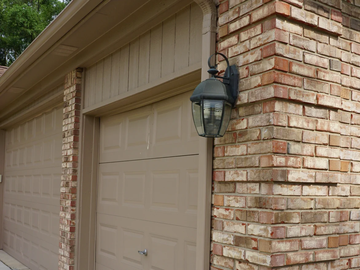 An outside corner beside the garage in 2019, the brick evenly blended on both faces below a carriage lamp