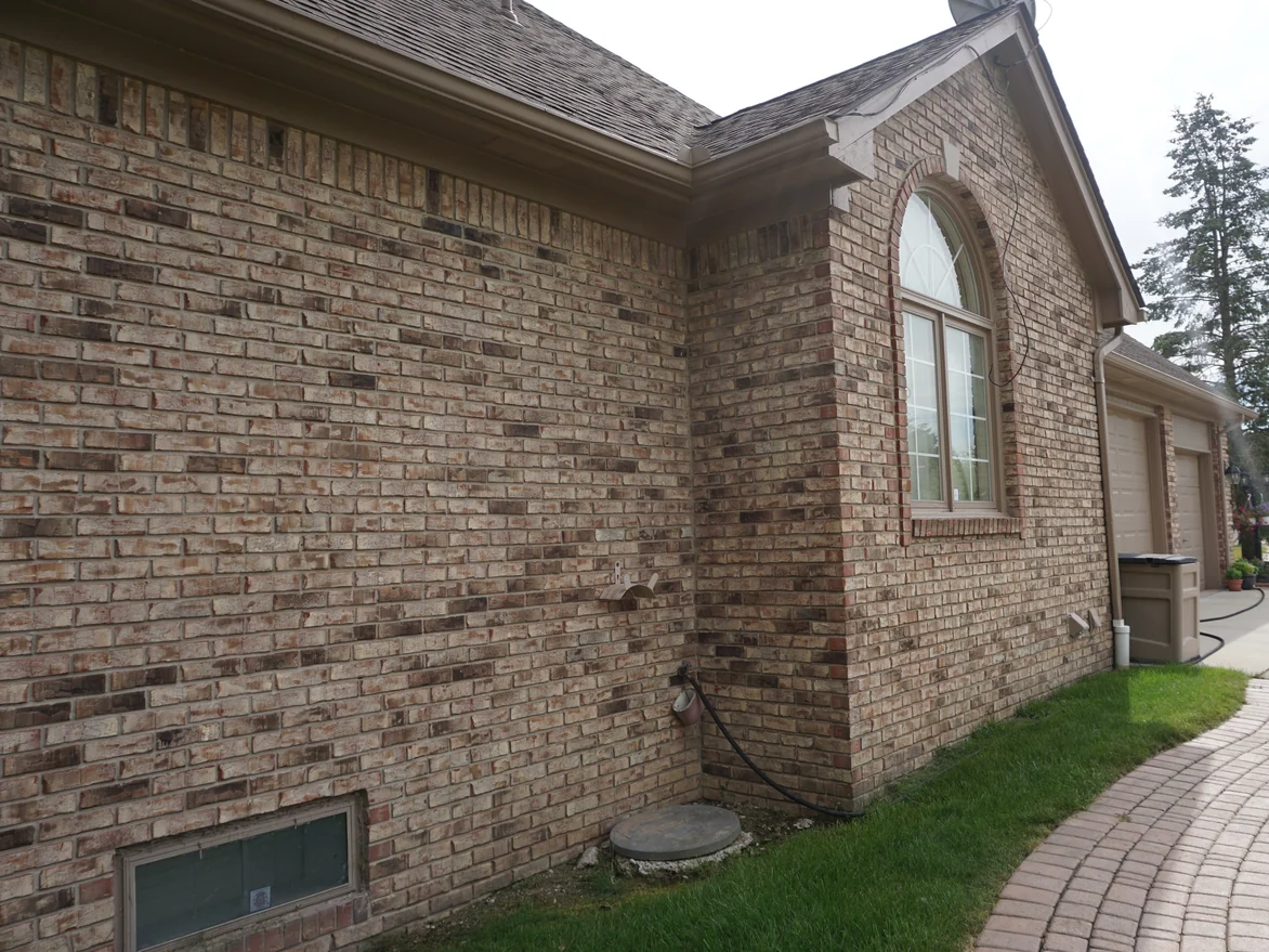 The long side wall of the house in 2019, an even range of tan, cream and brown units running back to the arched window in the gable