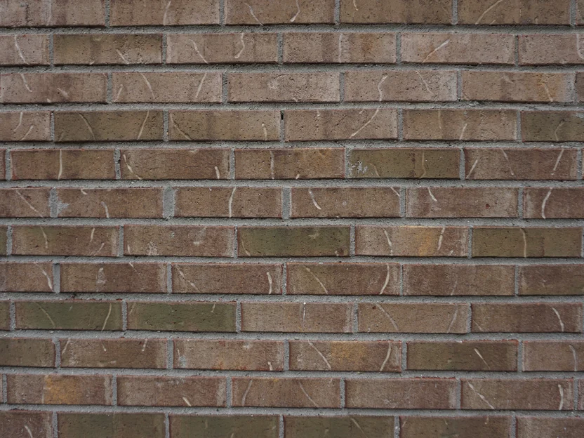 Close view of the wall in 2019, tan, olive and brown units running in courses with pale grey mortar joints