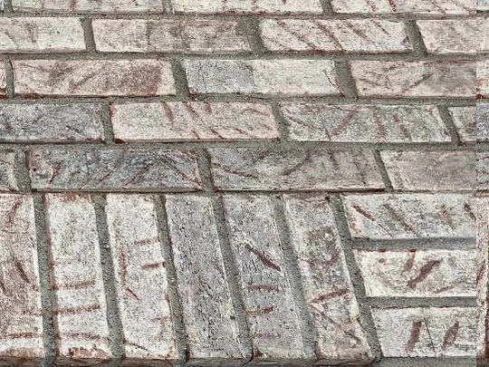 A second close-up in 2021, the band of dark brick lightened and the pale units brought down so the courses read together, the stain sitting in the brick rather than on it