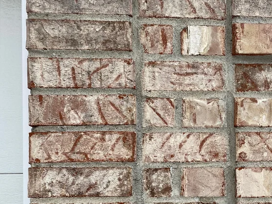 A close-up of the wall in 2021, the same salmon and cream brick now carrying a tan and grey blend with the brick texture and the tooling marks still showing through