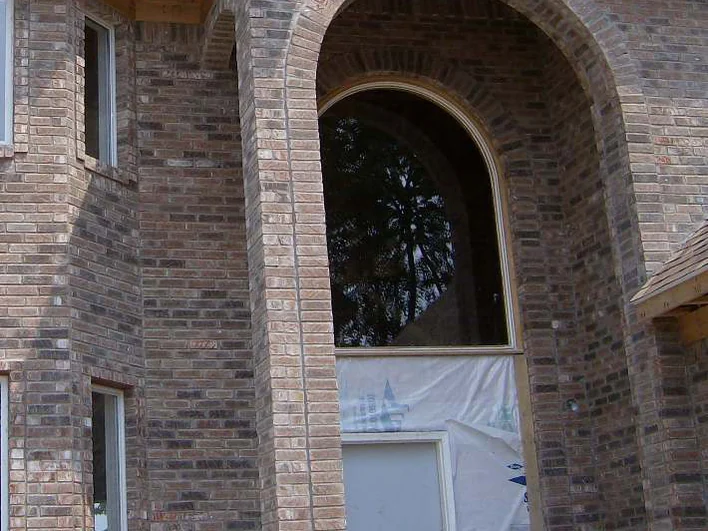The arched entry bay in 2007 with plastic sheeting across the doorway, the arch ring and the wall beside it made up of brick in several different colors