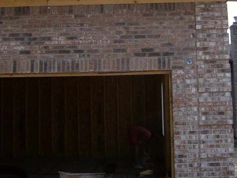The garage opening in 2007 with no door fitted and bare sheathing inside, the header course and the pier beside it mixing pink, cream and dark brown brick