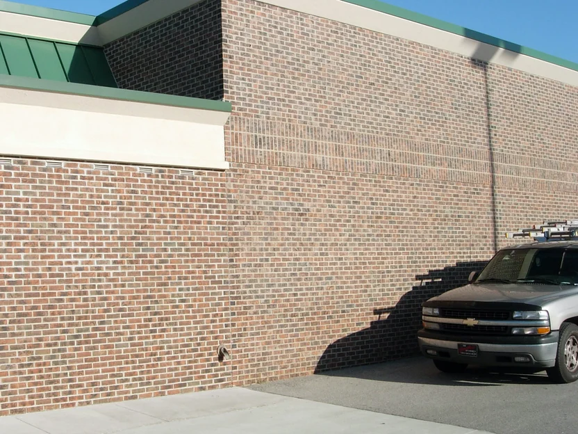 The same corner in 2007 after staining, the addition wall and the original wall with its soldier course reading as one red brown range, a pickup parked against the wall