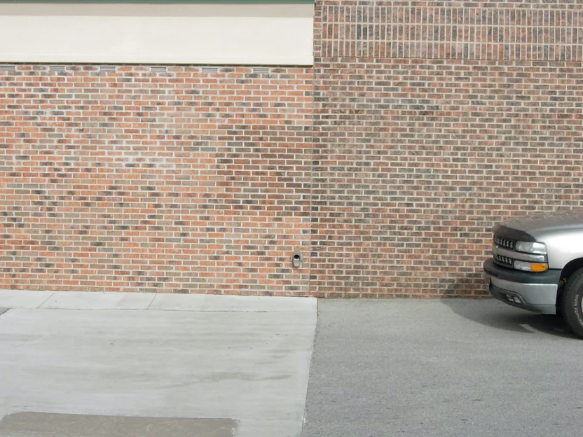 The joint between the addition and the original store in 2007, lighter orange brick under a cream fascia on the left meeting darker red brown brick with a soldier course on the right