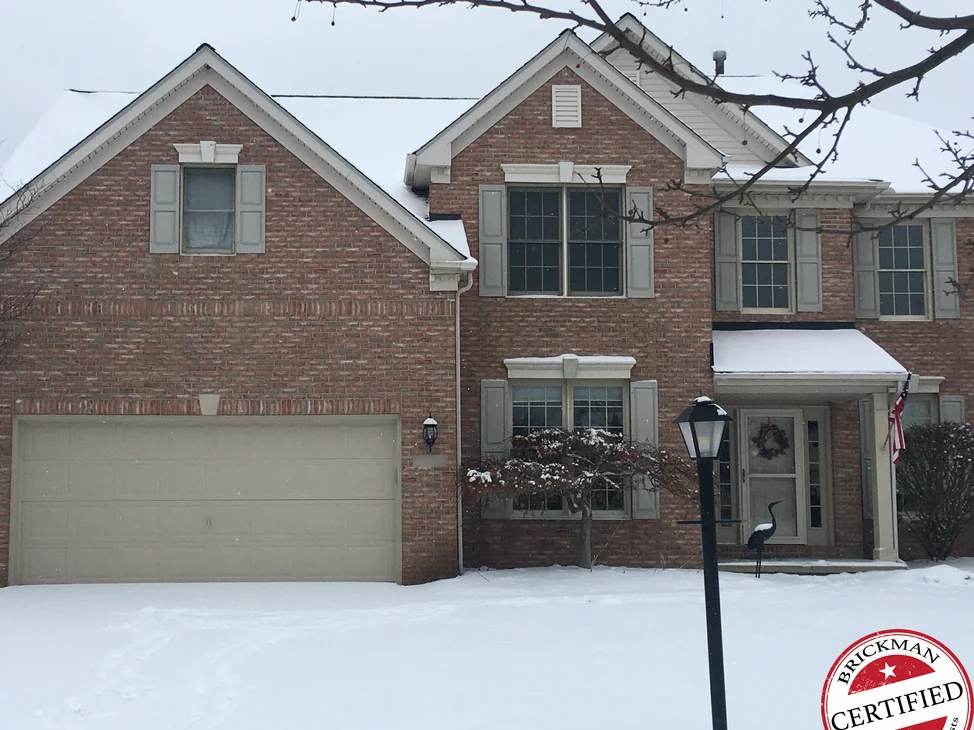 The whole front of the Strongsville house in 2020 under snow, the gable, the center bay and the garage wall reading as one pink salmon brick