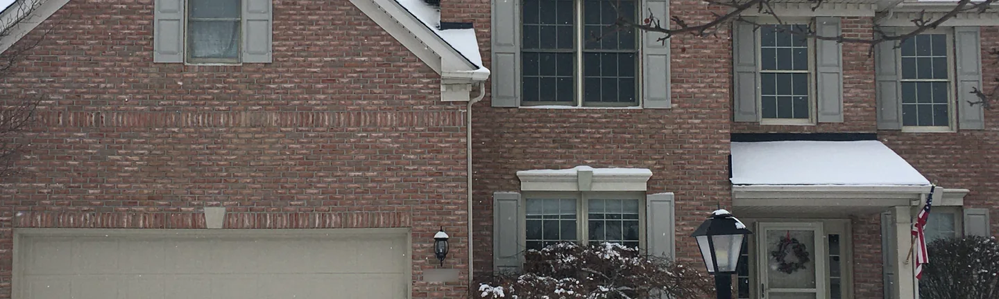 The front of the Strongsville home in 2020, its pink salmon brick running one range across the garage wall and the window bays under snow
