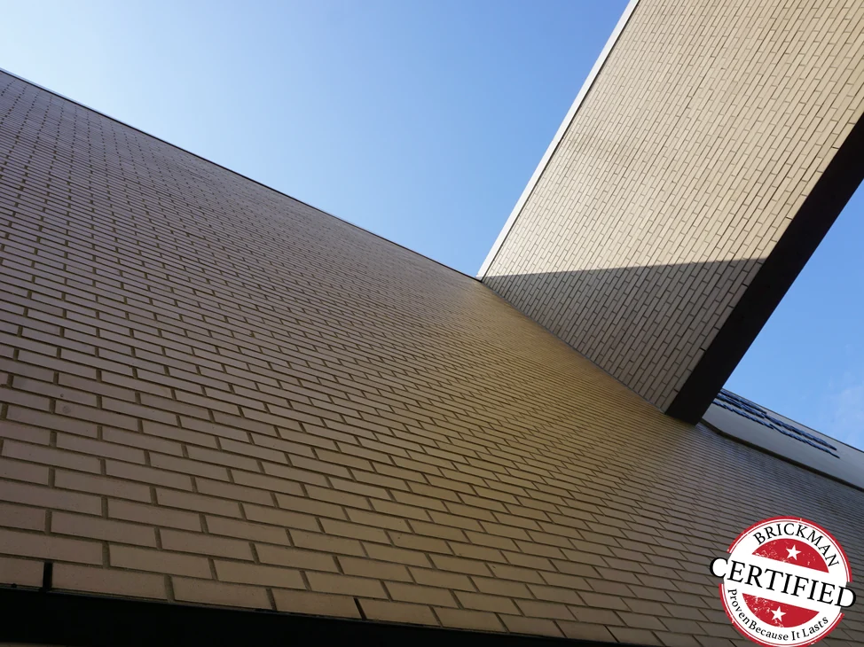The underside and brick fascia of the academy's entrance canopy in 2019, the courses running unbroken into the wing beyond it.