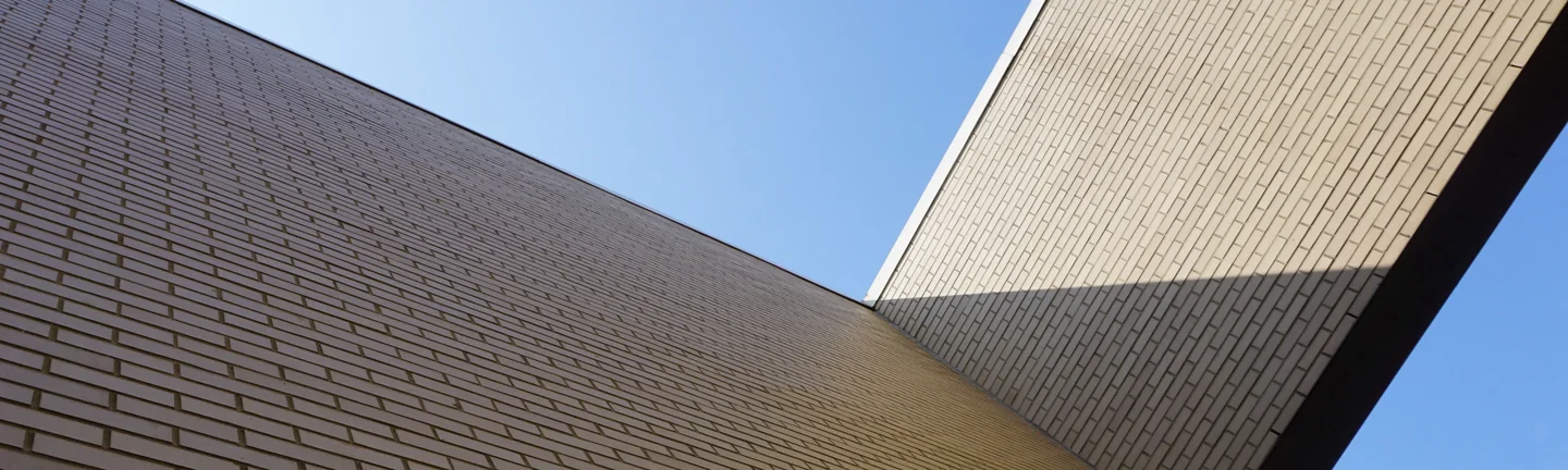 The brick fascia of the academy's entrance canopy in 2019, its courses reading as one even buff range against open sky