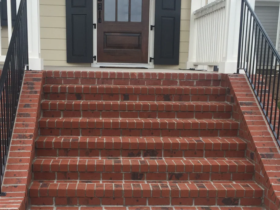 The new brick steps in 2015, a run of orange red brick treads rising to a dark front door, with dark spots scattered across the treads and the risers