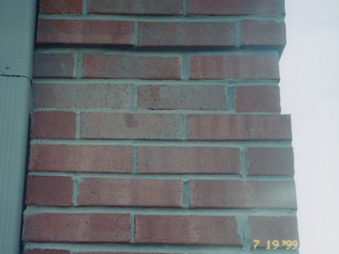A run of brick beside a downspout in July 1999, with grey and salmon units standing out from the red brick around them